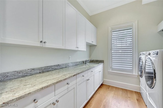 washroom featuring cabinet space, independent washer and dryer, a sink, light wood finished floors, and baseboards