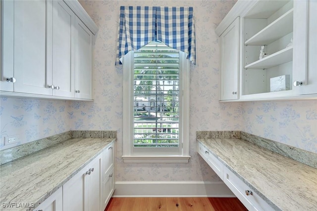 interior space with baseboards, wallpapered walls, and wood finished floors