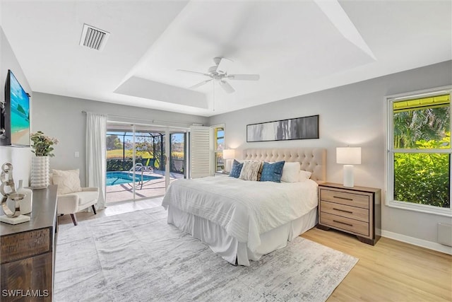 28389 Verde Ln, Bonita Springs, FL 34135 - bedroom featuring a tray ceiling, access to outside, light wood-style floors, baseboards, and a ceiling fan