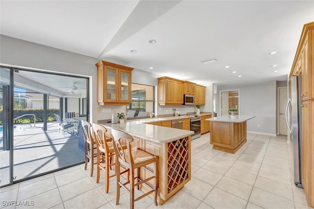 28389 Verde Ln, Bonita Springs, FL 34135 - kitchen with appliances with stainless steel finishes, light tile patterned flooring, a kitchen island, a peninsula, and a sink