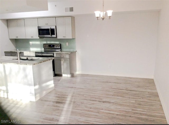 kitchen featuring stainless steel appliances, a chandelier, decorative backsplash, a sink, and visible vents