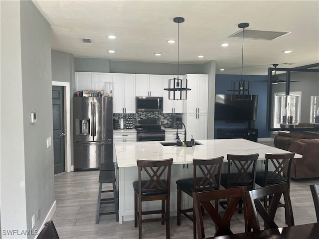 kitchen with visible vents, white cabinets, a sink, and stainless steel appliances