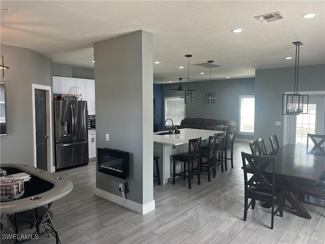 dining room with light wood finished floors, baseboards, visible vents, and recessed lighting