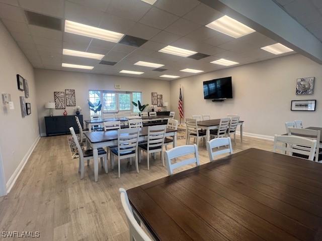 dining area featuring light wood-style floors, baseboards, and a paneled ceiling