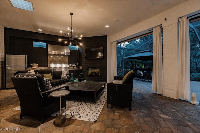 living area featuring a fireplace, an inviting chandelier, and stone tile flooring