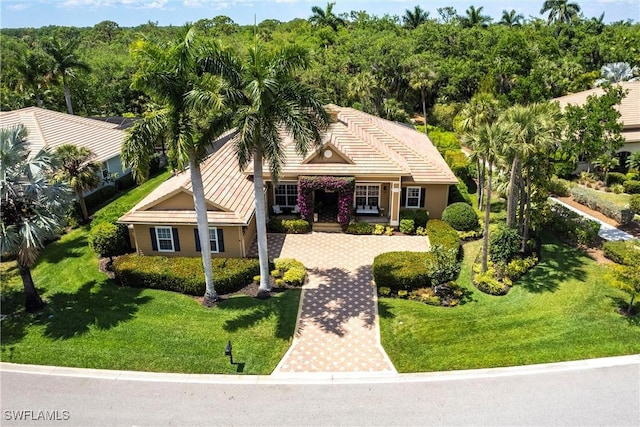 view of front facade with a tile roof, a front yard, and driveway