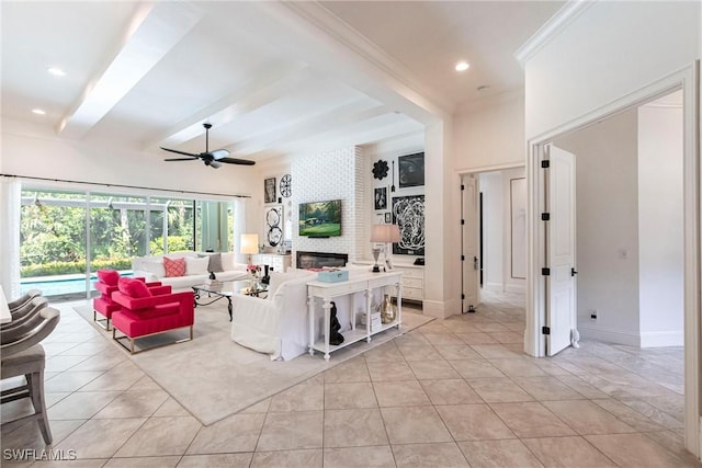 living area featuring baseboards, a ceiling fan, a large fireplace, and beamed ceiling