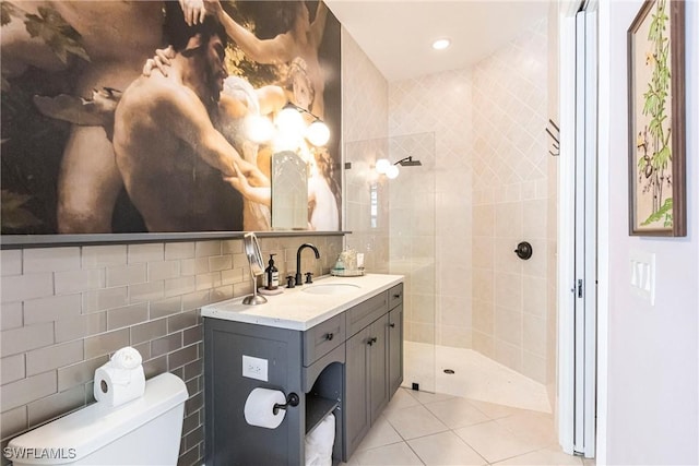 full bath featuring tile walls, a tile shower, toilet, vanity, and tile patterned flooring