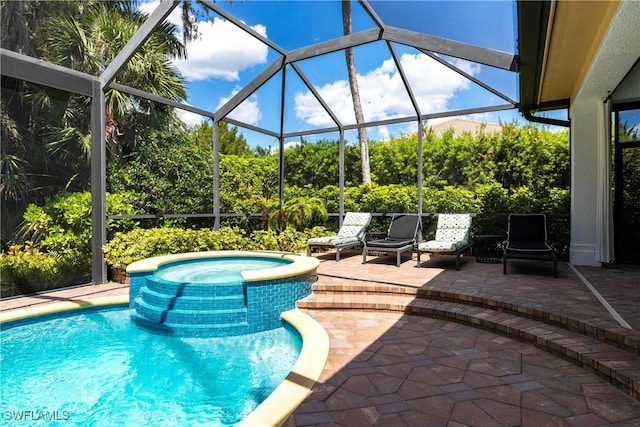 view of swimming pool featuring glass enclosure, a pool with connected hot tub, and a patio