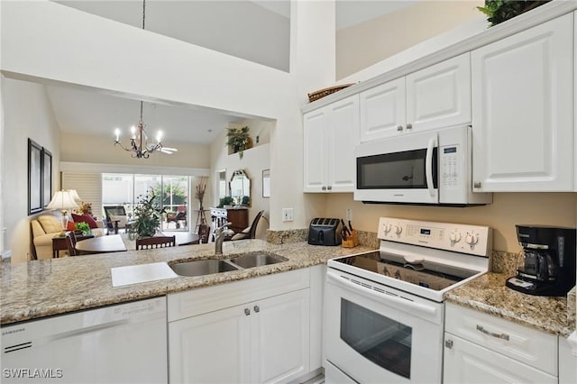 6103 Thresher Dr Unit 102, Naples, FL 34112 - kitchen with white appliances, a chandelier, vaulted ceiling, white cabinetry, and light stone countertops