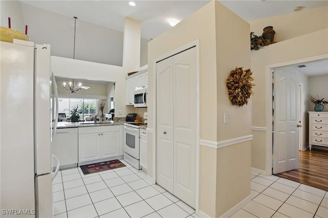 6103 Thresher Dr Unit 102, Naples, FL 34112 - kitchen with white appliances, light tile patterned floors, a chandelier, and white cabinets