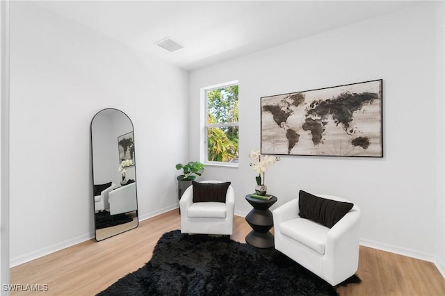 sitting room with baseboards, visible vents, and light wood finished floors