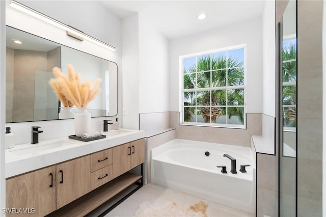 full bathroom with double vanity, a sink, a garden tub, and recessed lighting