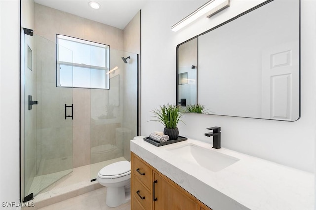 bathroom featuring a stall shower, toilet, and vanity