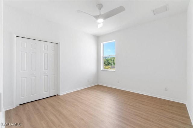 unfurnished bedroom with light wood-style flooring, baseboards, visible vents, a ceiling fan, and a closet