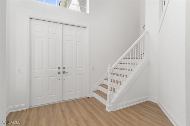 foyer featuring baseboards, wood finished floors, and stairway
