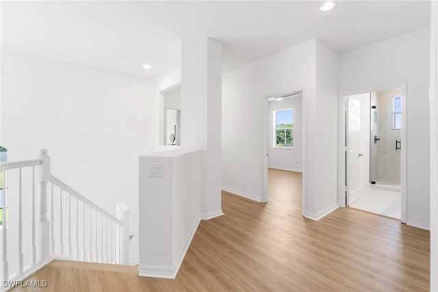 hallway with baseboards, an upstairs landing, light wood-style flooring, and recessed lighting