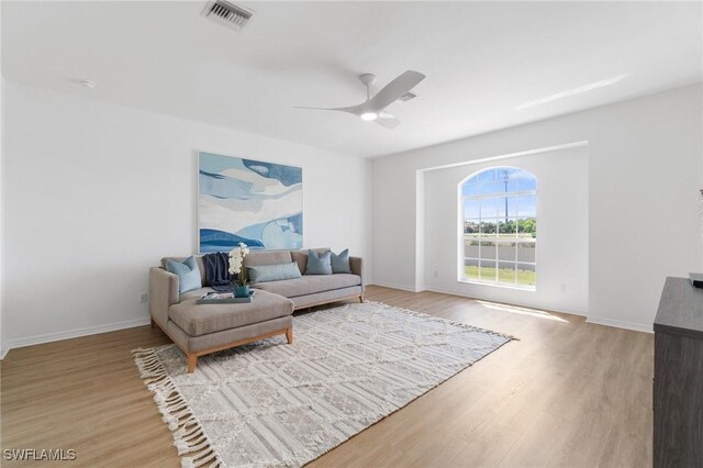 living room with baseboards, ceiling fan, visible vents, and light wood-type flooring