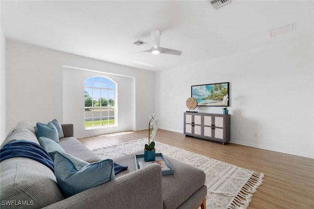 living area with baseboards, visible vents, wood finished floors, and ceiling fan