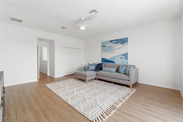living area with baseboards, light wood-style flooring, visible vents, and a ceiling fan