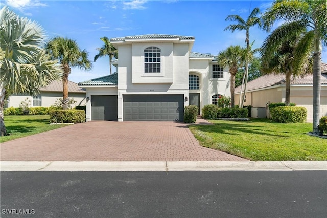 mediterranean / spanish-style home with a front lawn, decorative driveway, and a tiled roof