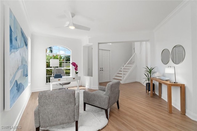 living area with crown molding, stairway, a ceiling fan, baseboards, and light wood-style floors