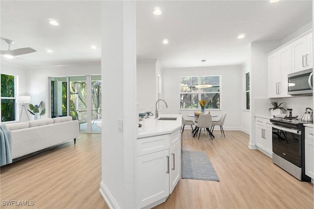 kitchen featuring open floor plan, light countertops, appliances with stainless steel finishes, and light wood-type flooring