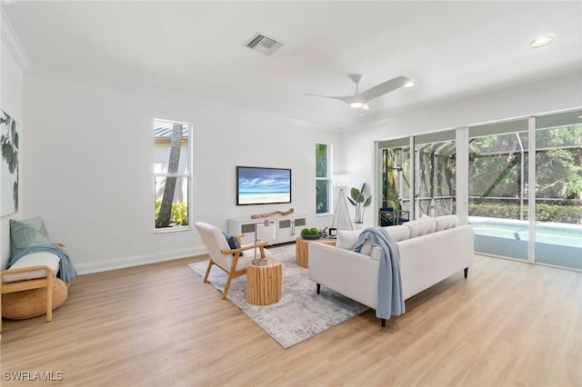 living area featuring baseboards, visible vents, a ceiling fan, and light wood finished floors