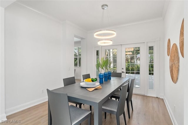 dining space with ornamental molding, baseboards, light wood finished floors, and a wealth of natural light