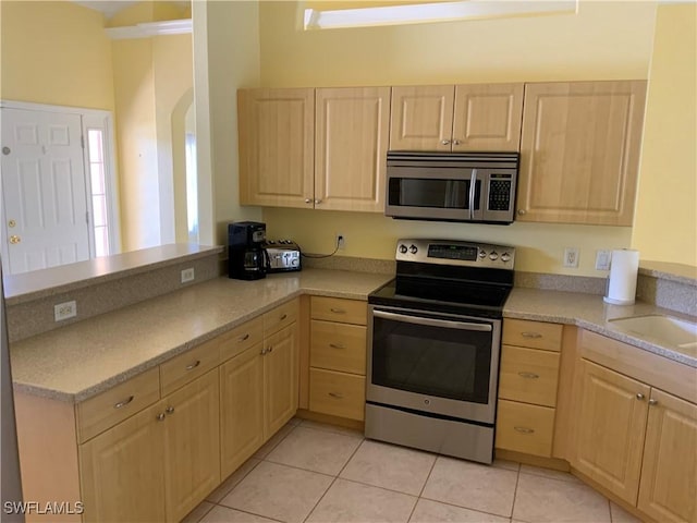 3817 NW 46th St, Cape Coral, FL 33993 - kitchen with stainless steel appliances, light brown cabinets, a peninsula, and light countertops