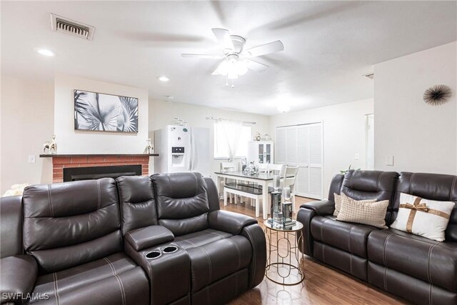 living room with a ceiling fan, a fireplace, wood finished floors, visible vents, and recessed lighting