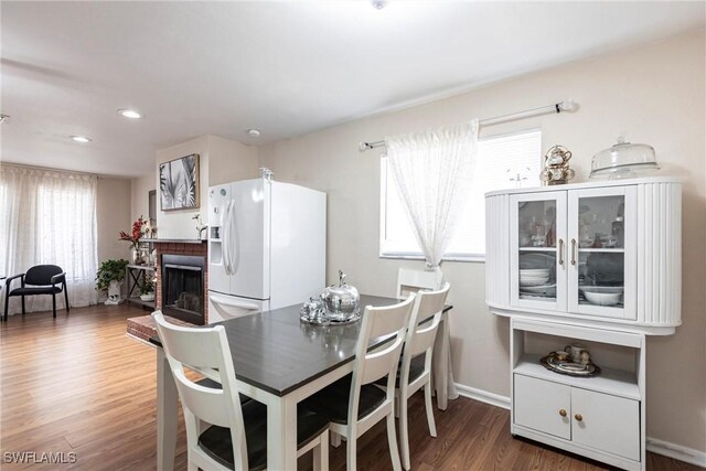 dining room featuring recessed lighting, baseboards, a fireplace, and wood finished floors