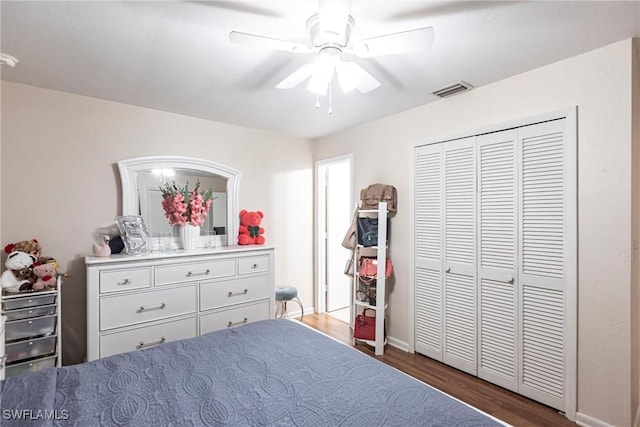 bedroom featuring a closet, wood finished floors, baseboards, visible vents, and ceiling fan