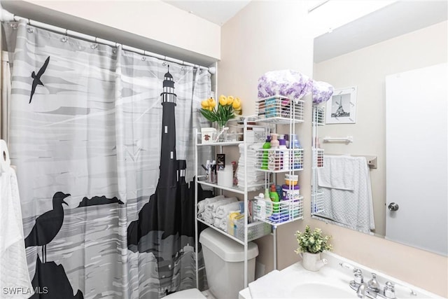 bathroom featuring a shower with curtain, toilet, and a sink