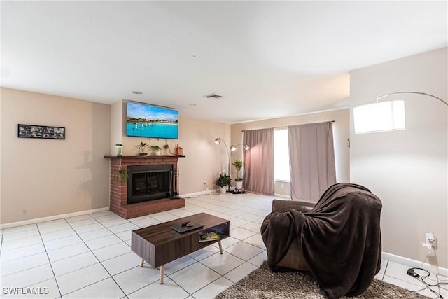 living room with light tile patterned flooring, baseboards, visible vents, and a brick fireplace