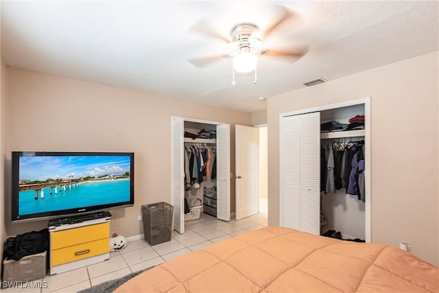 tiled bedroom featuring two closets, baseboards, ceiling fan, and visible vents