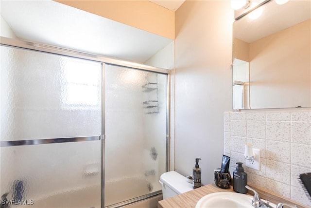 bathroom with backsplash, toilet, vanity, and bath / shower combo with glass door