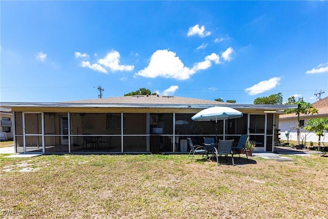 rear view of house featuring a sunroom and a yard