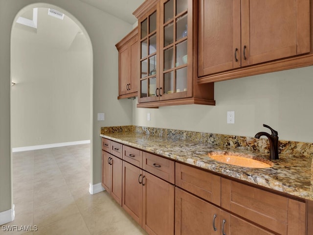 866 Cal Cove Dr, Fort Myers, FL 33919 - kitchen with arched walkways, light stone countertops, baseboards, and a sink