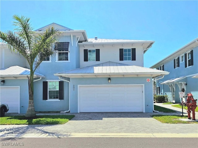 view of front facade with metal roof, stucco siding, and decorative driveway
