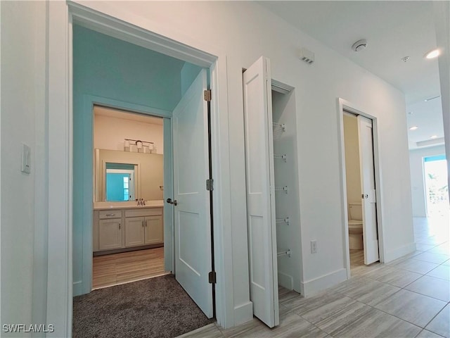 corridor featuring a sink, baseboards, and recessed lighting