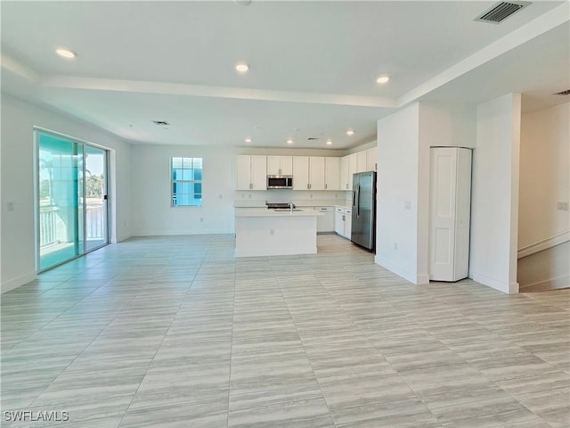 unfurnished living room with recessed lighting, visible vents, baseboards, and a sink