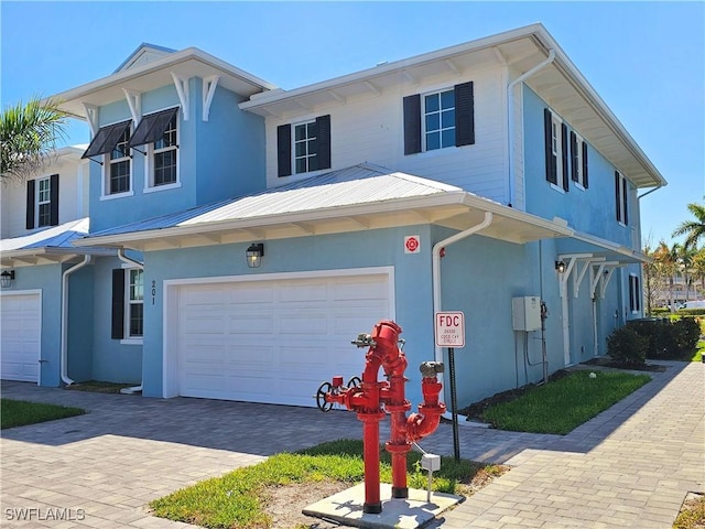 26330 Coco Cay Cir Unit 201, Bonita Springs, FL 34135 - view of front of home with a garage, stucco siding, driveway, and a metal roof