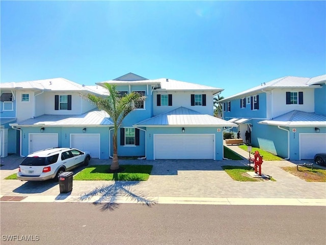 26330 Coco Cay Cir Unit 201, Bonita Springs, FL 34135 - view of front of home with decorative driveway, an attached garage, a metal roof, stucco siding, and a standing seam roof
