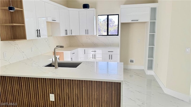 4802 Nora Ave N, Lehigh Acres, FL 33971 - kitchen with a peninsula, light marble finish flooring, light stone counters, decorative backsplash, and white cabinetry