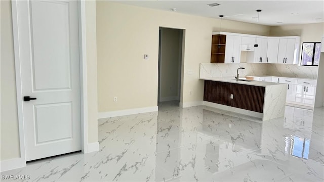 4802 Nora Ave N, Lehigh Acres, FL 33971 - kitchen featuring white cabinetry, light marble finish flooring, backsplash, light countertops, and hanging light fixtures