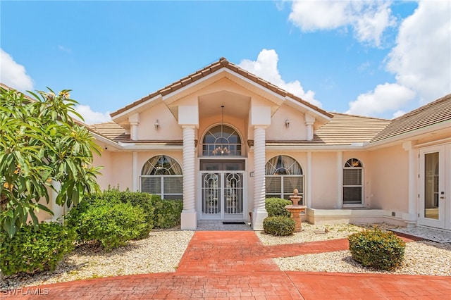 1207 SW 52nd Ter, Cape Coral, FL 33914 - view of exterior entry with french doors, a tiled roof, and stucco siding