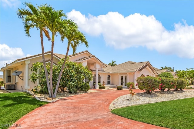 1207 SW 52nd Ter, Cape Coral, FL 33914 - view of front of house featuring a tiled roof, stucco siding, a front lawn, and french doors