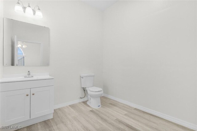 1207 SW 52nd Ter, Cape Coral, FL 33914 - bathroom featuring toilet, wood finished floors, vanity, and baseboards
