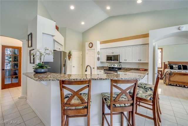 3914 SW 17th Ave, Cape Coral, FL 33914 - kitchen featuring light tile patterned flooring, a breakfast bar, appliances with stainless steel finishes, white cabinetry, and light stone counters